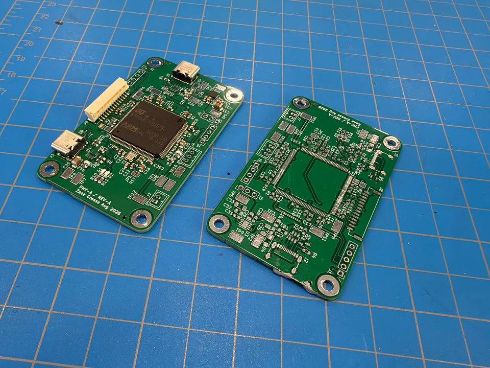 Partially assembled USB interface beside an unpopulated PCB on a blue cutting mat.